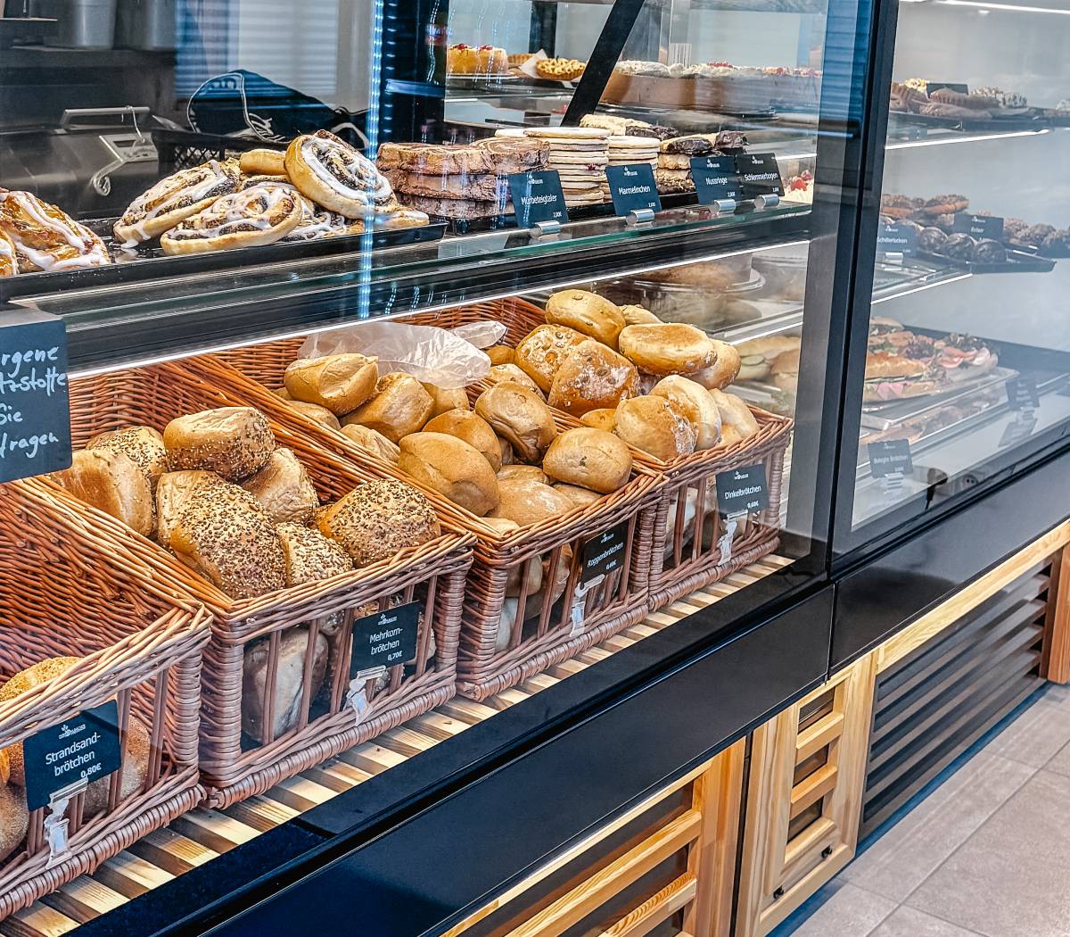Frische Brötchen und süßes Gebäck in Körben und Auslagen im Backshop