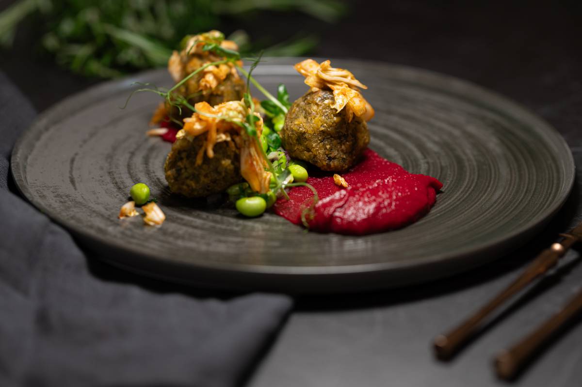 Vegetarische Kichererbsen-Haselnuss-Korianderbällchen auf cremiger Rote-Bete-Sauce mit Edamame und feinen Kräutern – modern angerichtet im Restaurant DÜNE 48 im DAS AHLBECK HOTEL & SPA