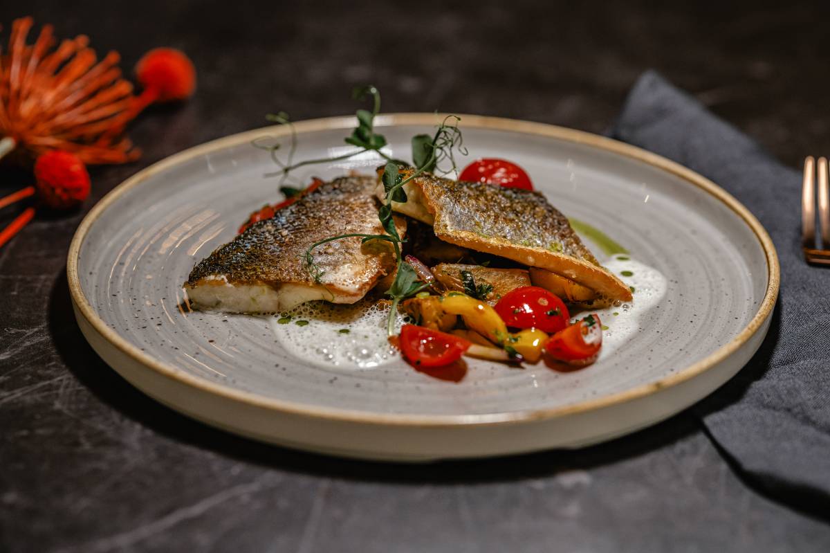 Gegrilltes Wolfsbarschfilet auf Zucchini, Tomate und Paprika, dazu in Aromen gebratene kleine Kartoffeln in der Düne 48