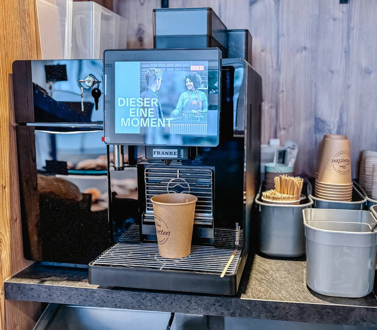 Moderne Kaffeemaschine im Backshop mit bereitstehendem Coffee-to-go-Becher