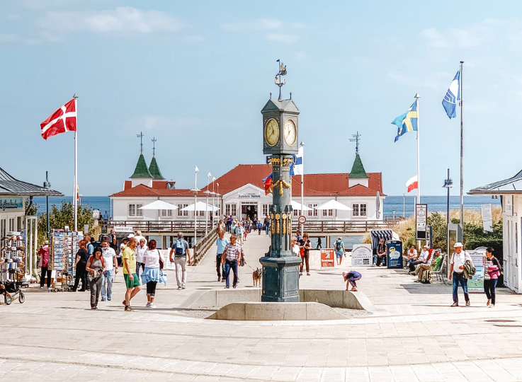 Historische Uhr auf der Promenade in Ahlbeck mit Blick auf die Seebrücke und Spaziergängern im Hintergrund