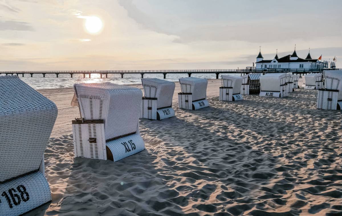 Weiße Strandkörbe am Ostseestrand vor der Seebrücke Ahlbeck auf Usedom bei Sonnenuntergang