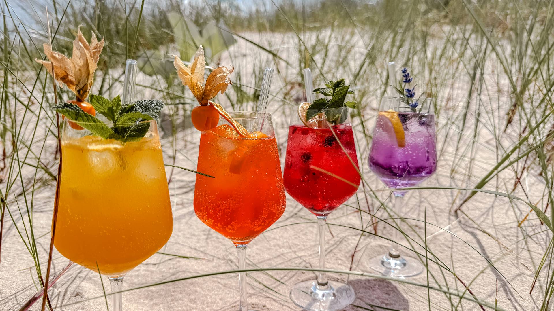 Ausgewählte Aperitifs und moderne Cocktails in bunten Farben im Günter’s im DAS AHLBECK HOTEL & SPA auf Usedom – serviert in Gläsern am Strand in den Dünen
