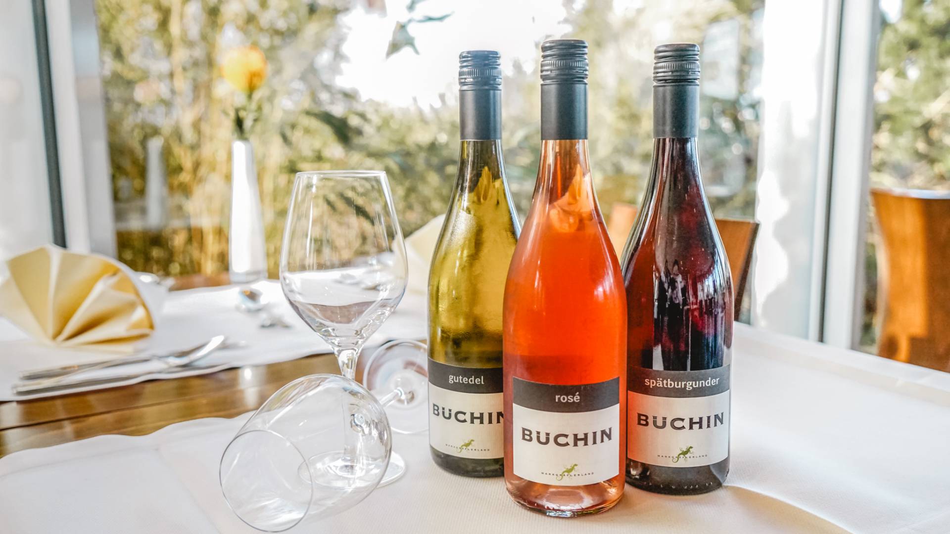 Feine Auswahl regionaler und internationaler Weine im Restaurant Düne 48 im DAS AHLBECK HOTEL & SPA – drei Flaschen Wein von Weingut Büchin auf elegant gedecktem Tisch