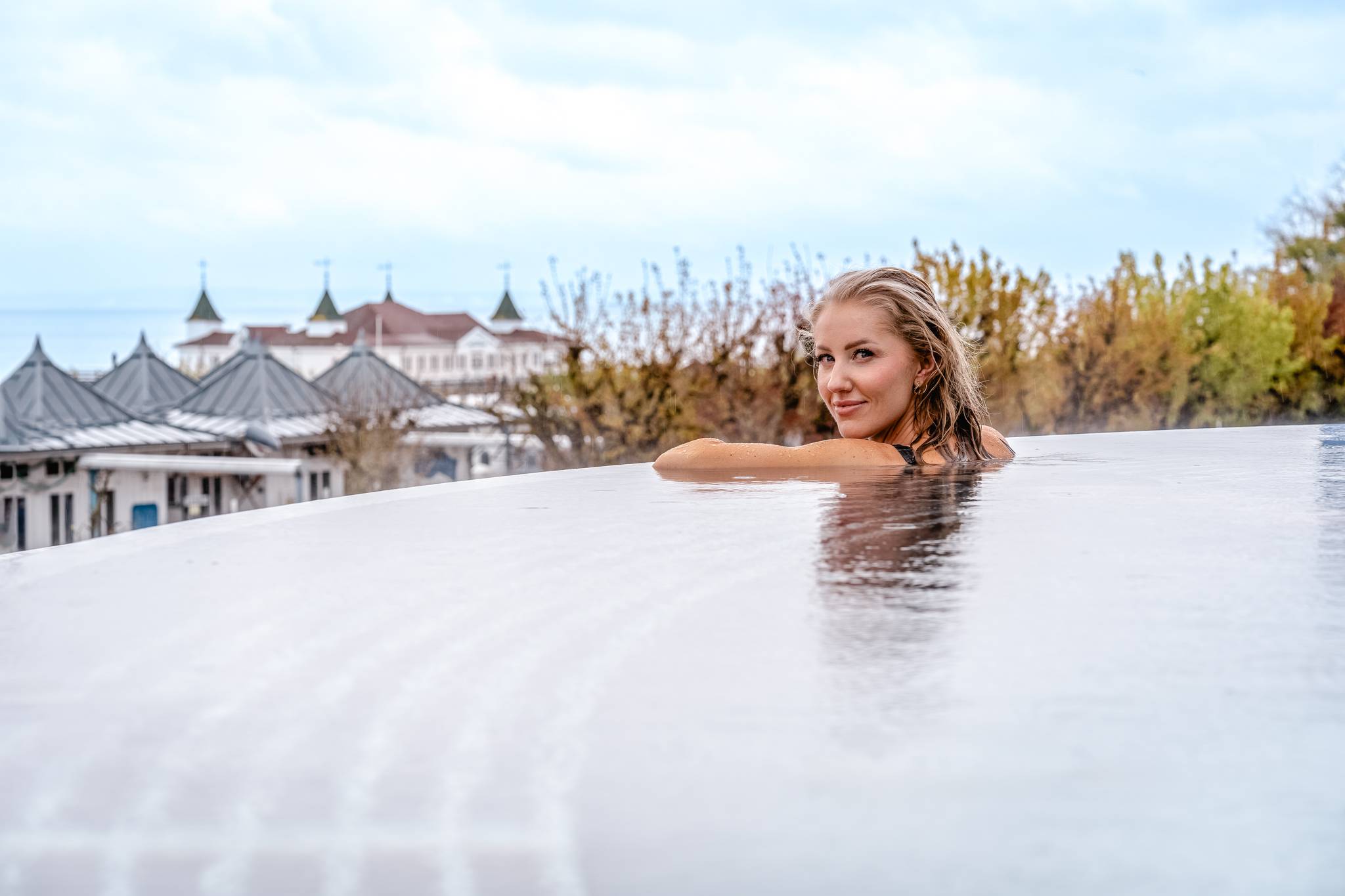 Frau entspannt im Infinity-Pool mit Blick auf die Seebrücke Ahlbeck und die Promenade an der Ostsee