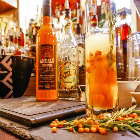 Erfrischender Sommer-Cocktail mit Sanddorn und Rosmarin im hohen Glas an der Bar des Günter’s im DAS AHLBECK HOTEL & SPA, dekorativ mit frischen Sanddornbeeren angerichtet