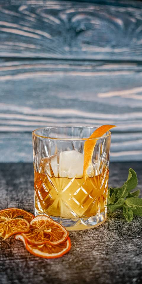 Eleganter Old Fashioned Cocktail im Kristallglas mit großer Eiskugel und Orangenzeste, stilvoll serviert im Günter’s im DAS AHLBECK HOTEL & SPA