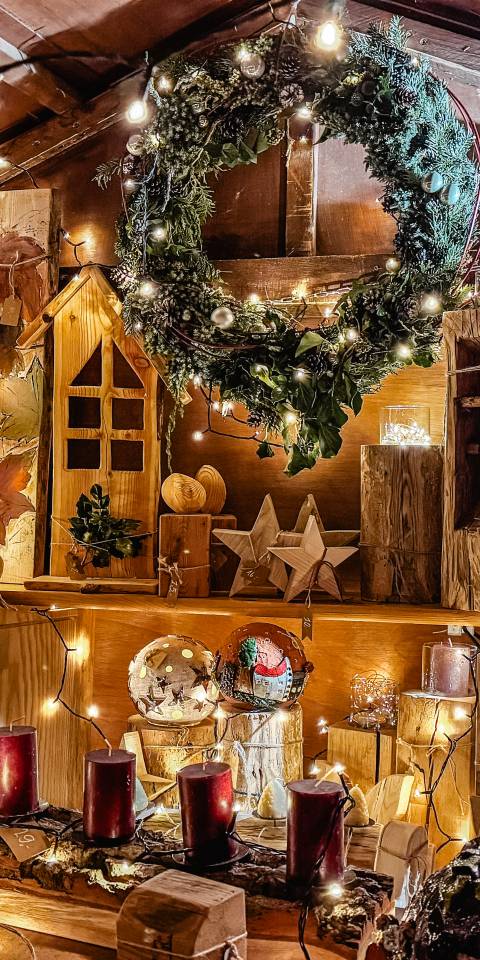 Dekorierte Holzbude zum Nikolausmarkt mit Lichterketten, Holzdeko z.B. aus Tannenbäumen, Sternen, Kerzenständern