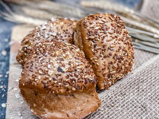Frische Mehrkornbrötchen vom DER AHLBÄCKER, mit Körnern bestreut und auf Leinentuch angerichtet