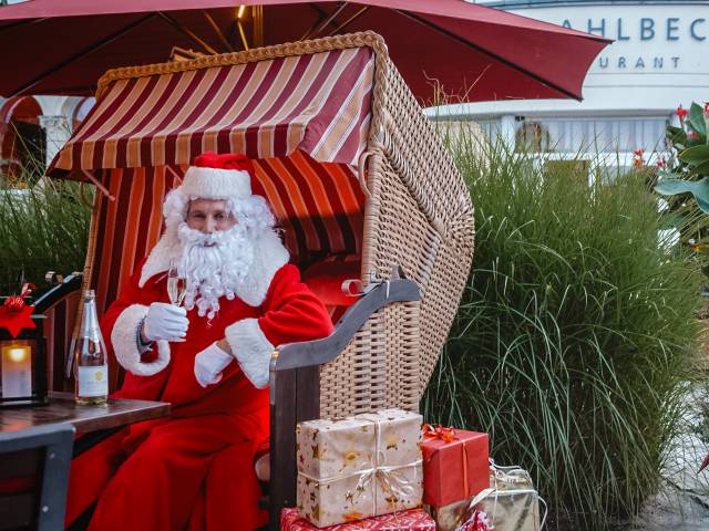 Weihnachtsmann im Strandkorb auf mit Geschenken und Glas Sekt auf der Hotelterrasse vom DAS AHLBECK HOTEL & SPA