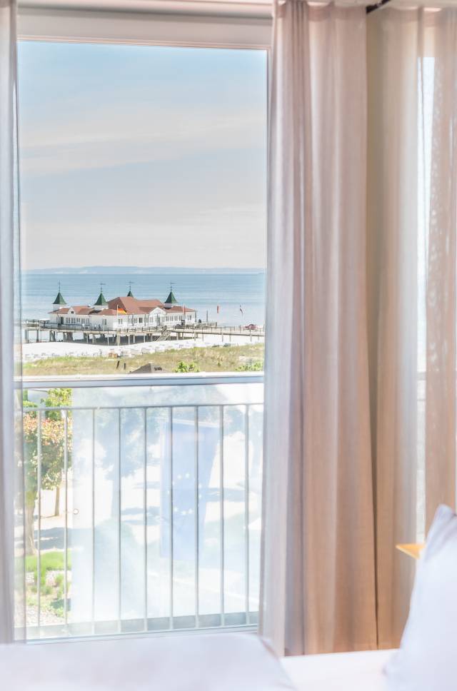Blick aus einem Hotelzimmer des Das Ahlbeck Hotel & Spa auf die Promenade, den Ostseestrand und die Seebrücke Ahlbeck