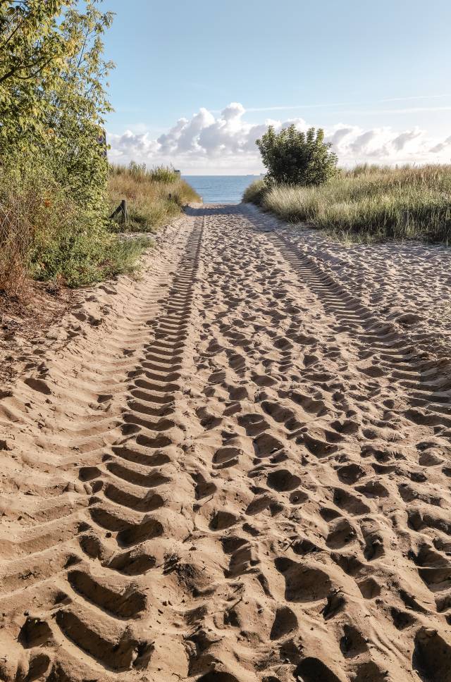 Sandiger Strandzugang auf der Insel Usedom mit Dünen und Blick auf die Ostsee unter blauem Himmel