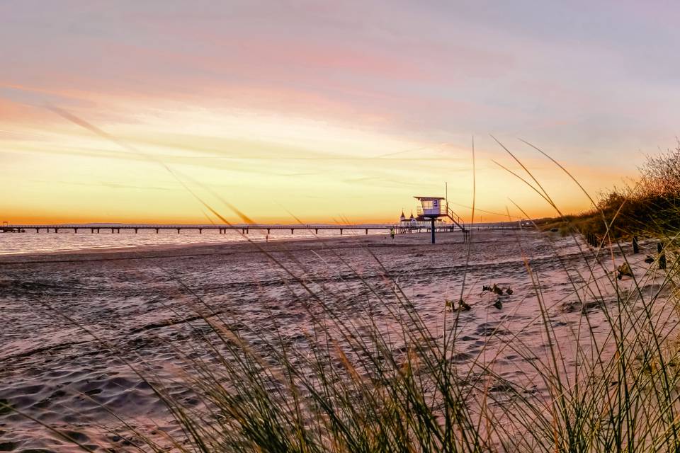 Strand von Ahlbeck auf Usedom mit Seebrücke im warmen Licht des Sonnenaufgangs und Dünen im Vordergrund