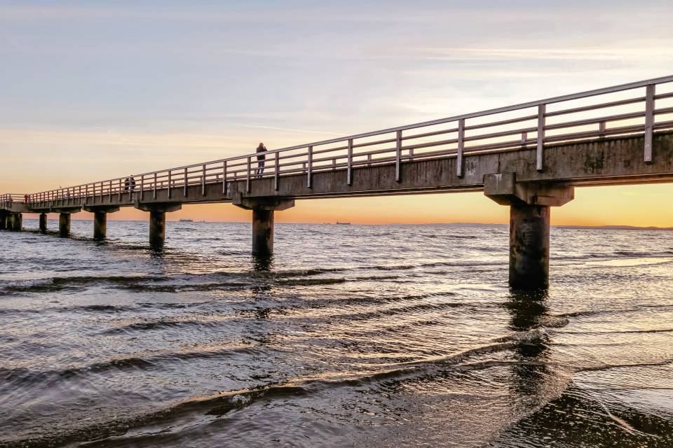 Seebrücke in Ahlbeck auf Usedom über der Ostsee bei warmem Abendlicht, mit sanften Wellen im Vordergrund