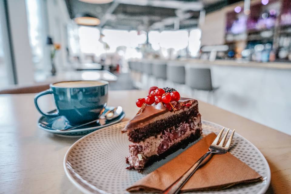 Stück Schoko-Kirsch-Torte mit Beeren und Schokoladenglasur, serviert mit Kaffee im Günter’s im DAS AHLBECK HOTEL & SPA