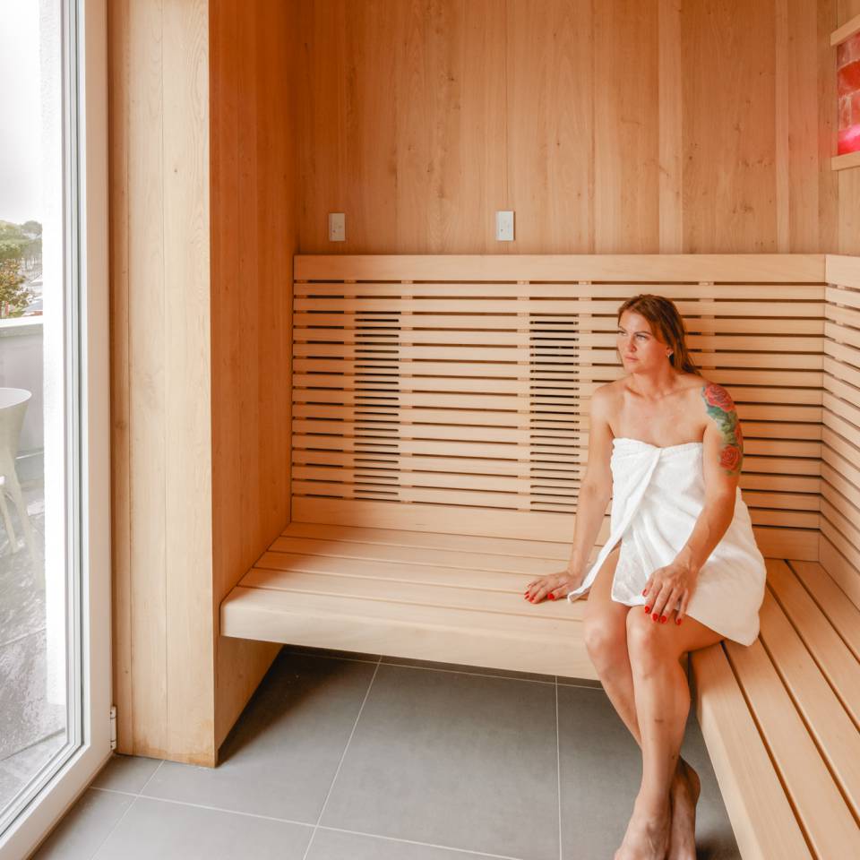 Entspannte Frau in der Infrarotsauna mit Blick auf Meer und Promenade im Das Ahlbeck Hotel & Spa****S