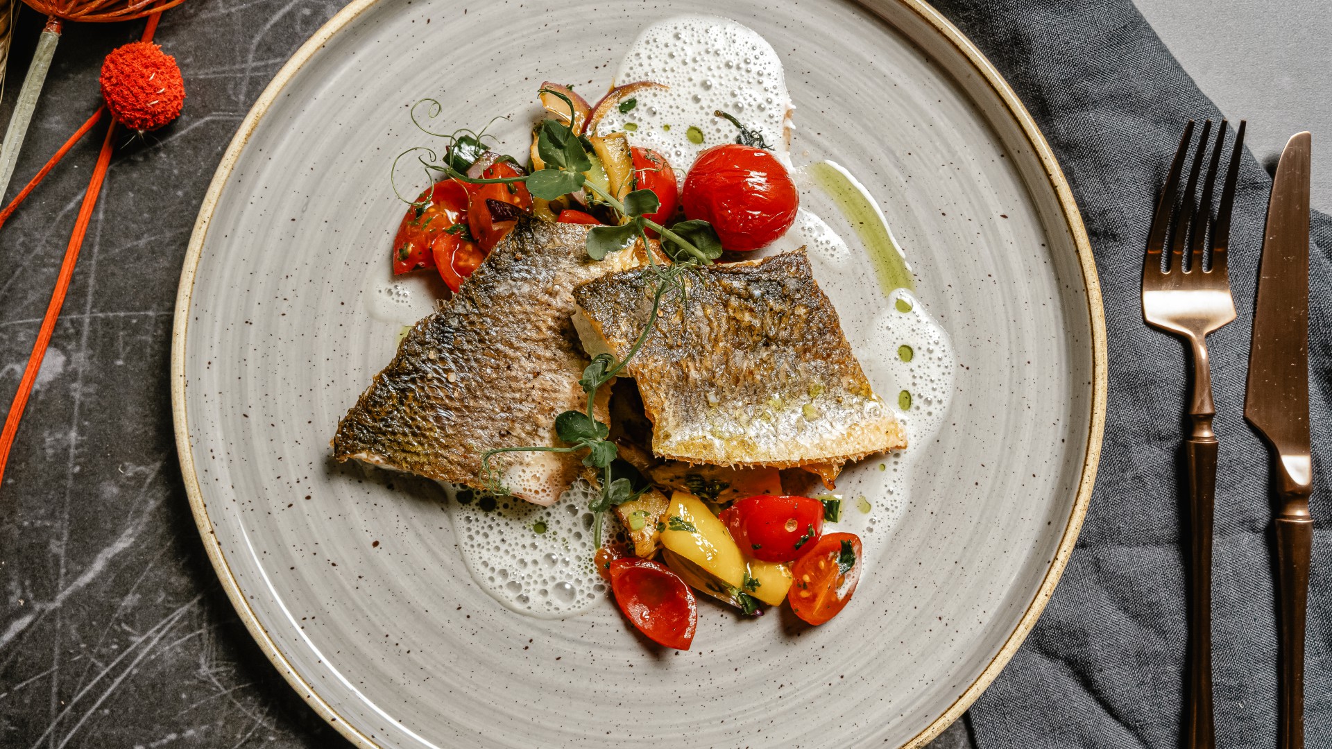 Gegrilltes Wolfsbarschfilet mit mediterranem Gemüse und Schaum auf elegant angerichtetem Teller im Restaurant Düne 48