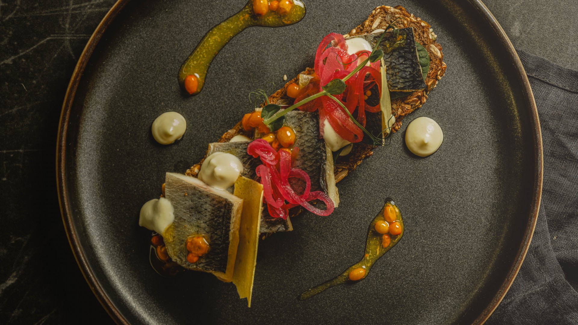 mariniertes-heringsfilet-mit-sanddornbeeren-einer-feinen-knoblauch-kartoffelcreme-und-eingelgten-zwiebeln-auf-volkornbrot in der Düne 48